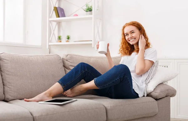 Genieten van de vrije tijd thuis. Gelukkig meisje met koffiekopje op de Bank — Stockfoto