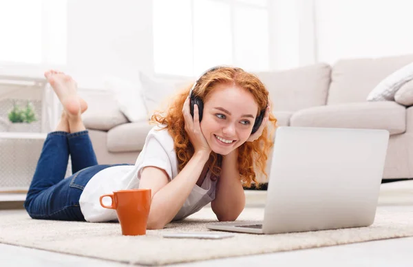 Ragazza in auricolare con computer portatile sdraiato sul pavimento — Foto Stock