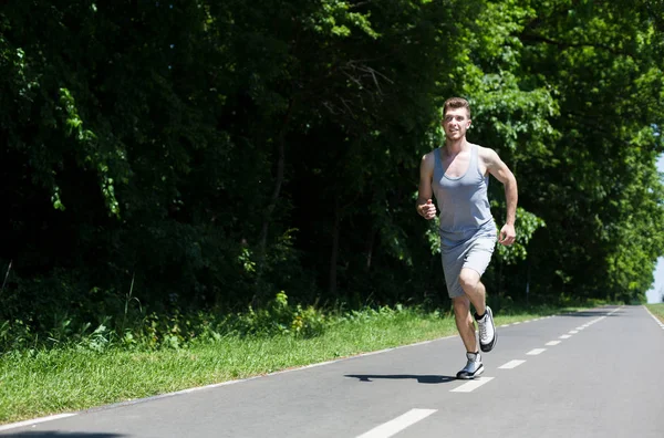 Junger Mann joggt auf Laufband im Park — Stockfoto