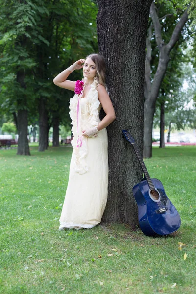 Portrait of beautiful boho girl near tree with blue guitar — Stock Photo, Image