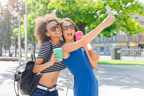 Счастливые девушки со смартфоном на открытом воздухе в парке — стоковое фото