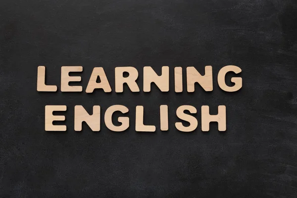 Het leren van Engels gespeld met houten letters op zwarte achtergrond — Stockfoto