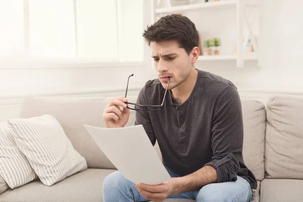 Jovem empresário cansado leitura relatório em casa — Fotografia de Stock