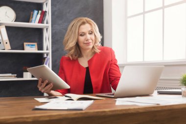 Dizüstü bilgisayarda çalışan ve dijital tablet tutan mutlu işkadını