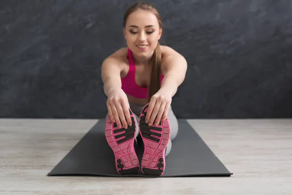 Mujer fitness feliz estiramiento en el fondo gris en interiores — Foto de Stock