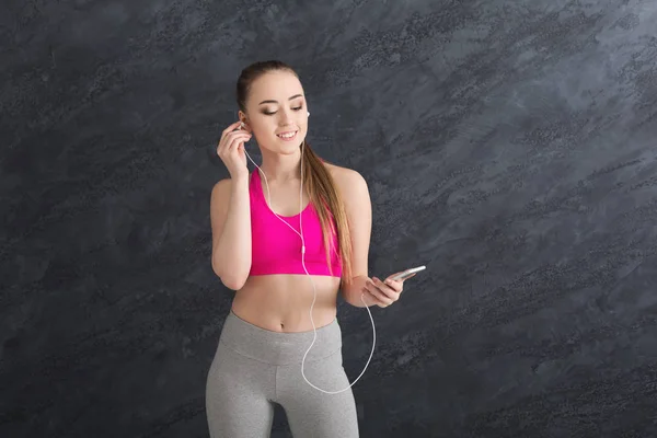 Γυμναστήριο κορίτσι στα ακουστικά ακούγοντας μουσική σε smartphone — Φωτογραφία Αρχείου