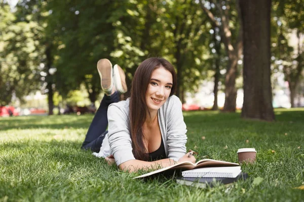 Молода жінка читає книгу lyinf в парку — стокове фото