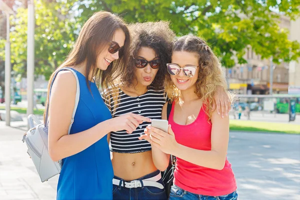 Счастливые подруги со смартфоном на открытом воздухе — стоковое фото