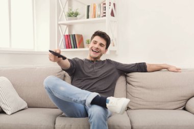 Genç adam uzaktan kumanda kullanarak tv izlerken