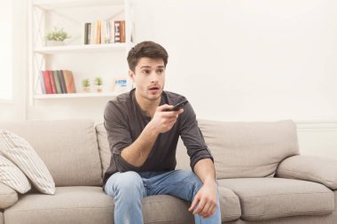 Genç adam uzaktan kumanda kullanarak tv izlerken