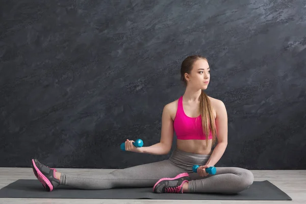 Mujer fitness con mancuernas sobre fondo gris en interiores — Foto de Stock