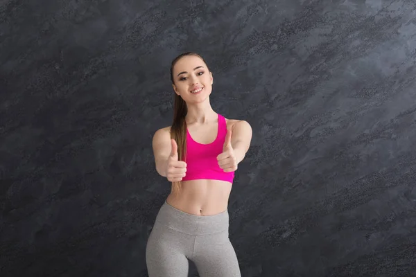 Mujer deportista feliz mostrando el pulgar hacia arriba sobre fondo gris —  Fotos de Stock