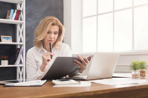 O femeie de afaceri atentă citește documentul pe desktop-ul de birou — Fotografie, imagine de stoc