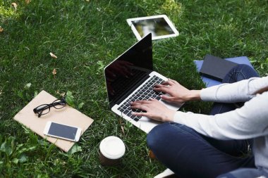 Parkta dizüstü bilgisayar kullanan genç dalgın kadın