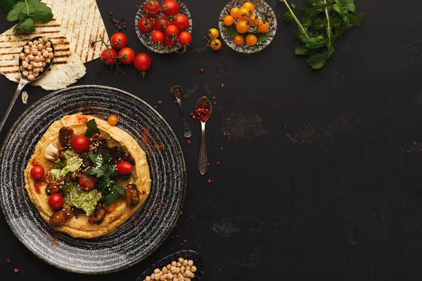 Hummus with vegetables and seafood on black background