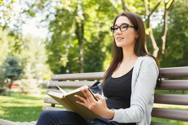 Молода жінка читає книгу в парку копіювати простір — стокове фото