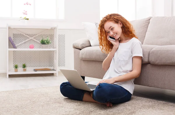 Ragazza felice utilizzando computer portatile e telefono sul pavimento — Foto Stock