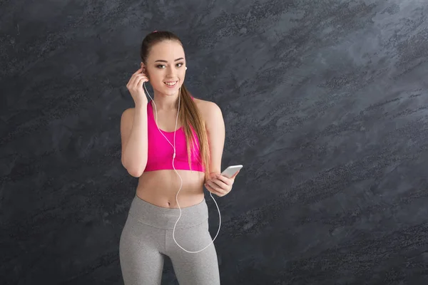 Happy fitness girl in earphones listening music on smartphone — Stock Photo, Image
