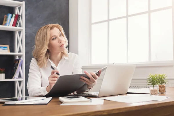 Thoughtful businesswoman reading document at office desktop — Stock Photo, Image