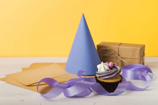 Läcker cupcake och gåva på gul bakgrund — Stockfoto