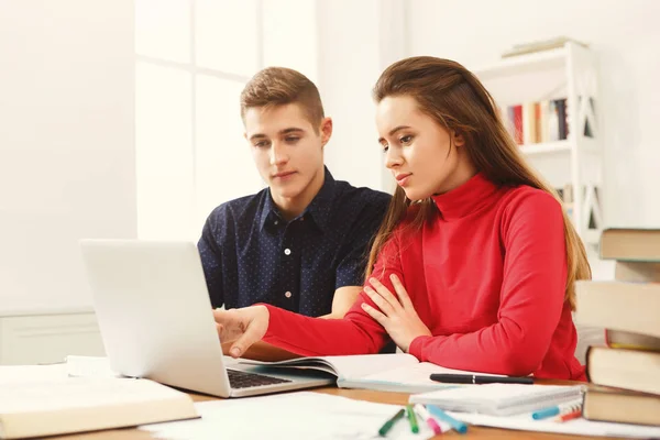 Mannelijke en vrouwelijke studenten aan houten tafel vol met boeken — Stockfoto