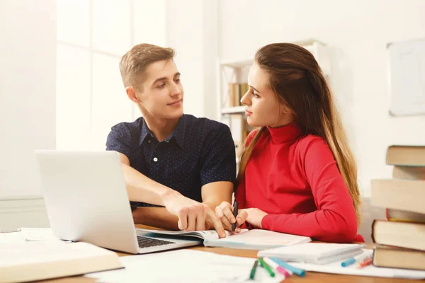 Mannelijke en vrouwelijke studenten aan houten tafel vol met boeken — Stockfoto