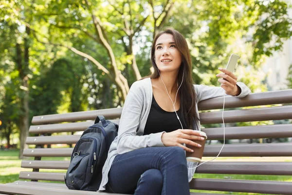 Estudante sentado no parque e usando smartphone — Fotografia de Stock