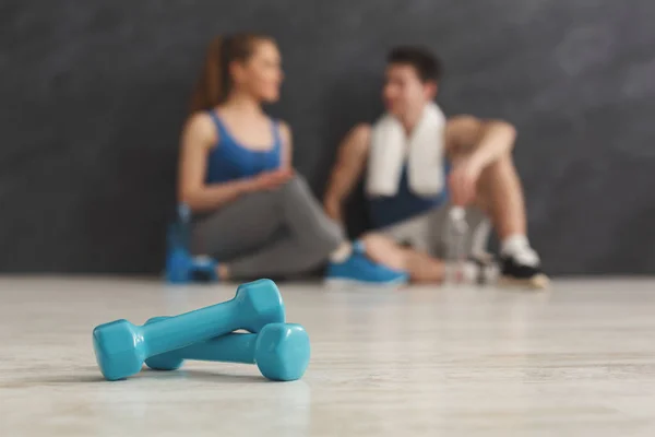 Two dumbbells and blurred couple at gym — Stock Photo, Image