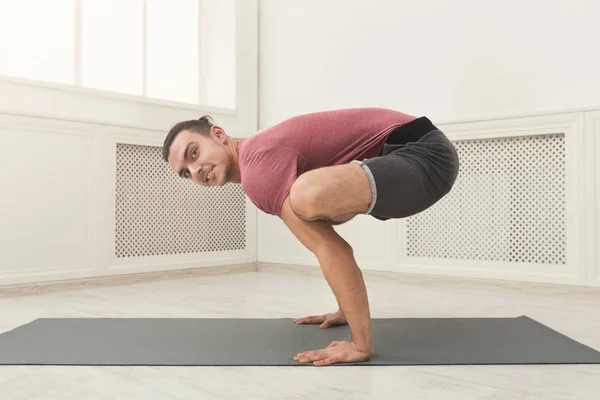 Ung man stående i Bakasana motion — Stockfoto