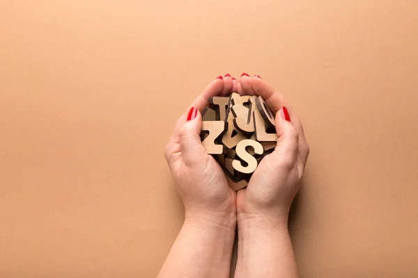Mulher segurando letras de madeira no fundo bege — Fotografia de Stock