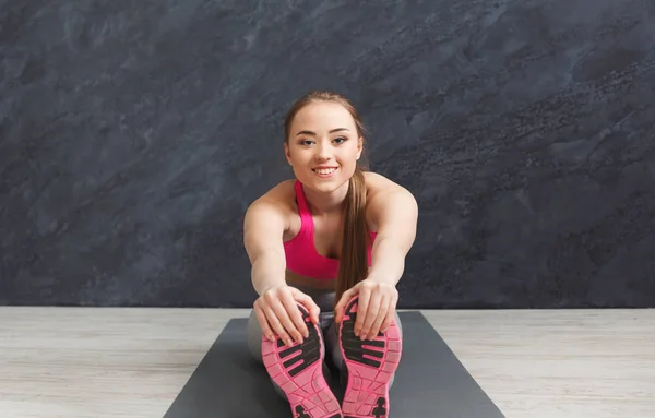 Boldog fitness nő a nyújtás, zárt térben a szürke háttér — Stock Fotó