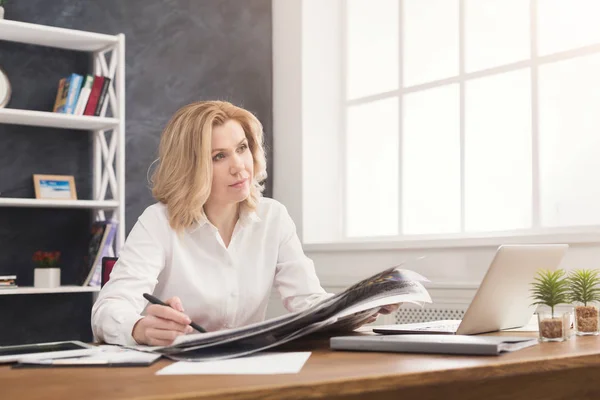 Nachdenkliche Geschäftsfrau liest Zeitung am Schreibtisch im Büro — Stockfoto