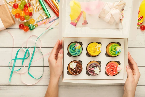 Sortimento de cupcakes saborosos com topos de creme de manteiga coloridos em mãos femininas — Fotografia de Stock