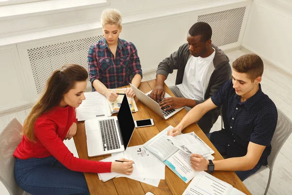 Grupo de estudiantes diversos que estudian en la mesa de madera — Foto de Stock