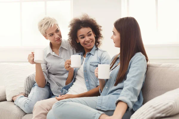 Tre unga kvinnliga vänner med kaffe chatta hemma — Stockfoto