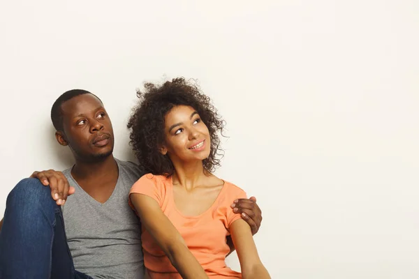 Black couple looking up sitting on floor — Stock Photo, Image