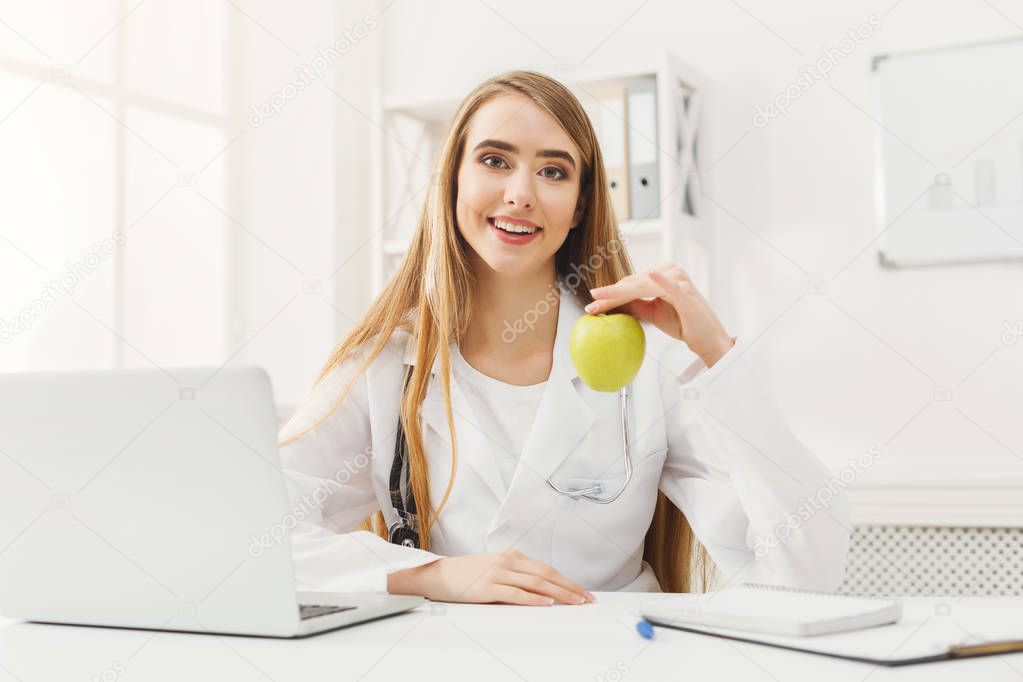 Smiling nutritionist woman with apple at office