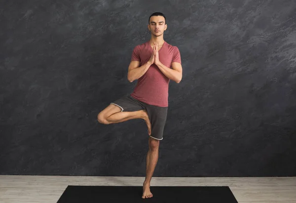 Ung man utbildning yoga i tree pose — Stockfoto