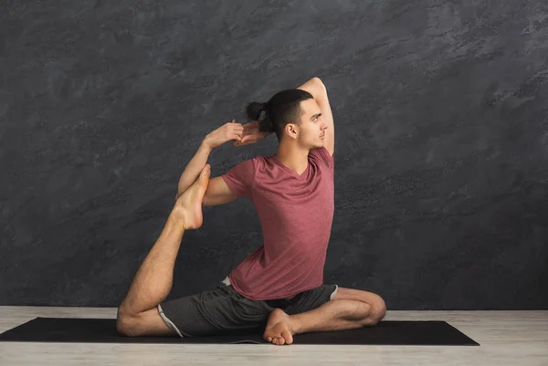 Jeune homme flexible pratiquant le yoga au gymnase — Photo