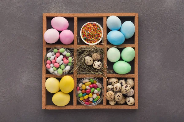 彩色复活节彩蛋和小糖果框架上的灰色背景 — 图库照片