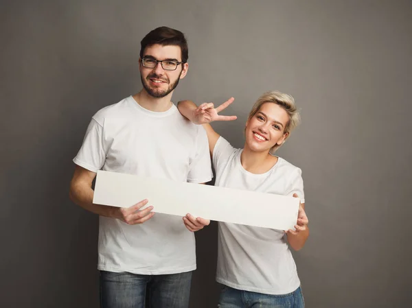 Młoda para trzymając pusty biały sztandar — Zdjęcie stockowe