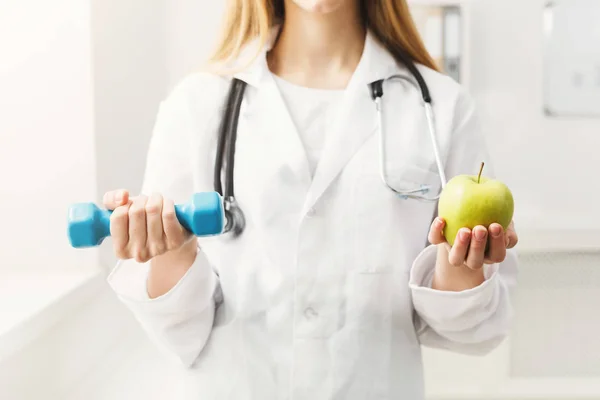 Jeune diététiste avec pomme et haltère à la clinique — Photo