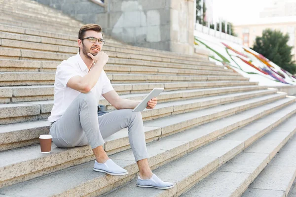 Guapo empresario reflexivo utilizando tableta al aire libre — Foto de Stock