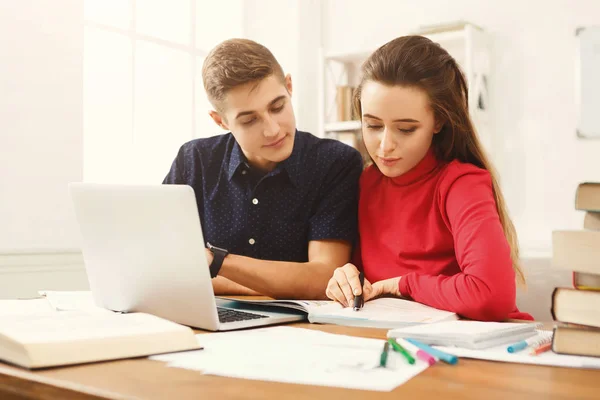 Mannelijke en vrouwelijke studenten aan houten tafel vol met boeken — Stockfoto