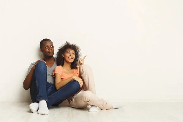 Pareja negra mirando arriba sentada en el suelo —  Fotos de Stock