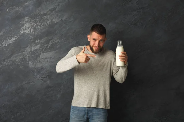 Joven hombre guapo señalando en botella de leche —  Fotos de Stock
