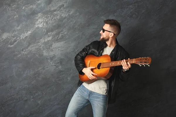 Schöner lächelnder Mann mit Gitarre posiert im Studio — Stockfoto