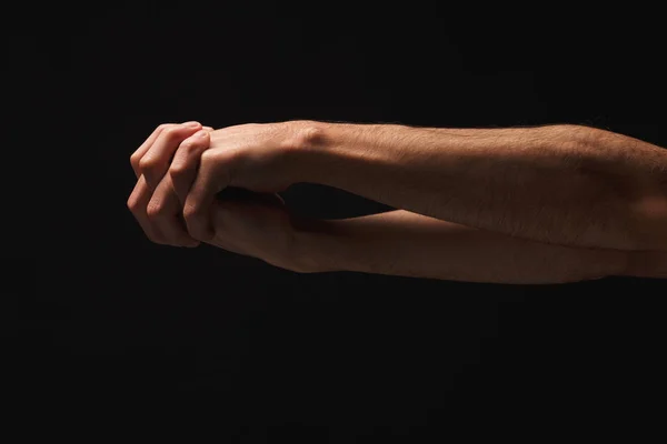 Чоловік тримає руки разом на чорному ізольованому тлі — стокове фото