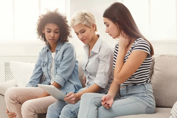 Drie verrast vriendinnen met tablet. — Stockfoto