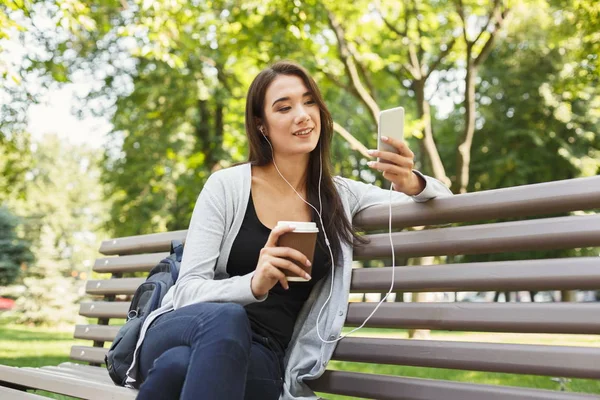 Diák ül a parkban, és használ smartphone — Stock Fotó